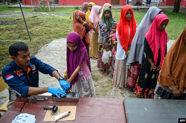 Pengungsi Rohingya mendaftarkan identitasnya ke petugas imigrasi di tempat penampungan sementara di Laweueng, Aceh 29 Desember 2022. (Foto: AFP)