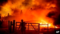FILE - A firefighter extinguishes flames as the Oak Fire crosses Darrah Rd. in Mariposa County, Calif., on July 22, 2022.