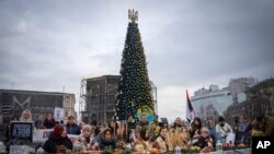 Relatives of soldiers from the Azov Regiment, who were captured by Russia in May after the fall of Mariupol, sit under the Christmas tree demanding to free the prisoners, in Kyiv, Ukraine, Dec. 24, 2022.