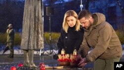 In this photo provided by the Ukrainian Presidential Press Office, Ukrainian President Volodymyr Zelenskyy and his wife, Olena, pay tribute at a monument to victims of the Holodomor, Great Famine, that killed millions, in Kyiv, Ukraine, Nov. 26, 2022.