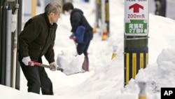 Residents shovel snow off a sidewalk in Kanazawa, Ishikawa prefecture, central Japan, on Dec. 24, 2022.