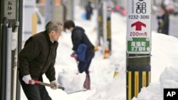 Stanovnici skidaju snijeg s trotoara u centralnom dijelu Japan, 24. decembra 2022. (Kyodo News preko AP-a)