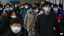 Masked commuters walk through a walkway in between two subway stations as they head to work during the morning rush hour in Beijing, Tuesday, Dec. 20, 2022. (AP Photo/Andy Wong)