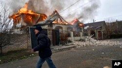Lokalni stanovnik trči pored zapaljene kuće pogođene ruskim granatiranjem u Khersonu, Ukrajina, 6. siječnja 2023.
