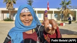 Une électrice tunisienne montre son doigt taché d'encre après avoir voté lors des élections législatives, dans un bureau de vote du district de Mnihla, à l'extérieur de Tunis, le 17 décembre 2022.