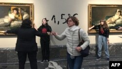 FILE - This handout picture released by Extinction Rebellion environmental movement on Nov. 5, 2022, shows two activists glued by their hands to the frames of two paintings by Spanish master Francisco Goya at the Prado museum in Madrid.
