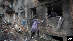 FILE - People gather their belongings from a damaged building after Russian shelling in the town of Vyshhorod, Ukraine, Nov. 24, 2022. The U.N. reports that more than 10 million Ukrainians are facing winter without water, heat or electricity.