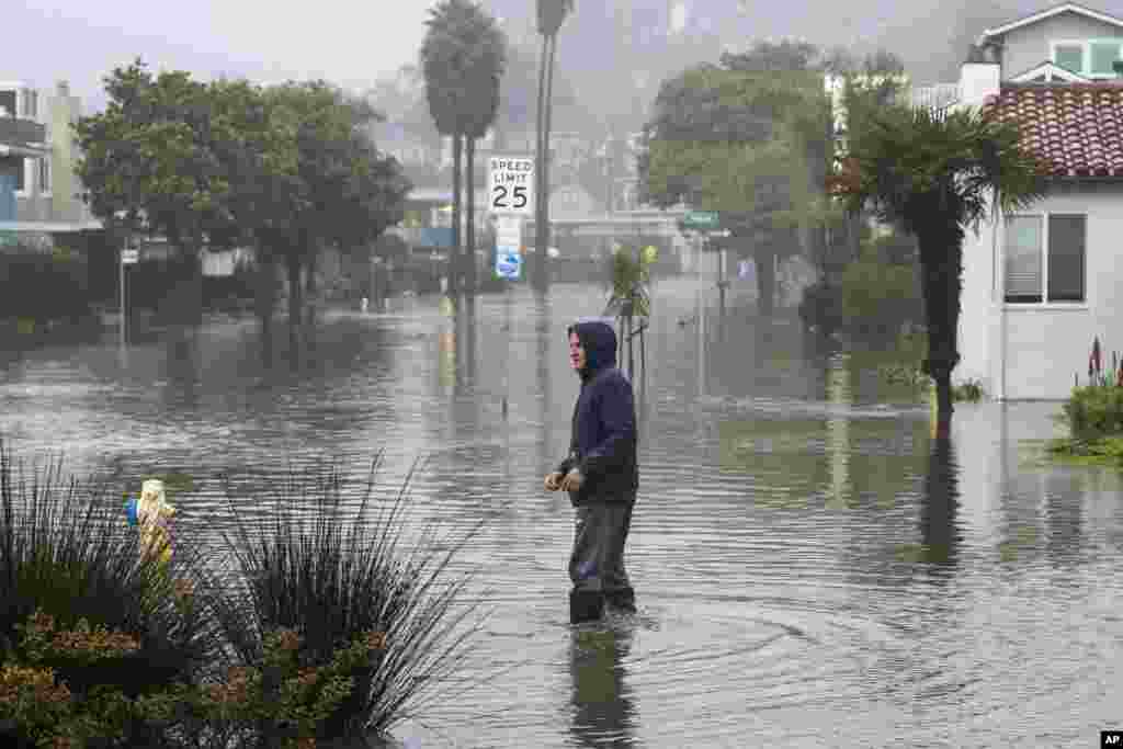 A man wades through a flooded street in the Rio Del Mar neighborhood of Aptos, Jan. 9, 2023.