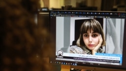 FILE - A woman looks at a computer screen showing undated video of Iranian journalist Nazila Maroufian, in Nicosia, Cyprus, Nov. 4, 2022.