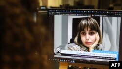 FILE - A woman looks at a screen image of Nazila Maroufian, detained in Iran for coverage of protests, Nov. 4, 2022. 