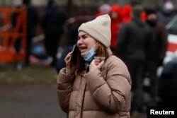 A woman reacts while talking on a phone at the site where an apartment block was heavily damaged by a Russian missile strike in Dnipro, Ukraine, Jan. 15, 2023.