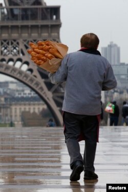 FILE - Seorang pria membawa roti baget (baguette), di dekat menara Eiffel di Paris, Prancis, 30 Maret 2016. REUTERS/Philippe Wojazer