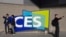 FILE - People take pictures in front of a sign during the CES tech show, in Las Vegas, on Jan. 6, 2022. CES is returning to Las Vegas in January 2023 with the hope that it inches closer to how it looked before the pandemic. 