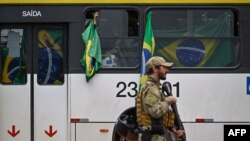 Supporters of Brazil's ex-president, Jair Bolsonaro, are taken in buses by police forces to the Federal police headquarters, in Brasilia, Brazil, on Jan. 9, 2023, a day after a pro-Bolsonaro mob rioted.