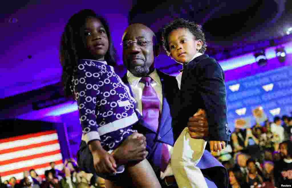 Сенаторот Рафаел Ворнок (Д-ГА) ги држи во раце својата ќерка Клои и неговиот син Кејлеб за време на изборната вечерна забава во Атланта, Џорџија, 6 декември 2022 година.