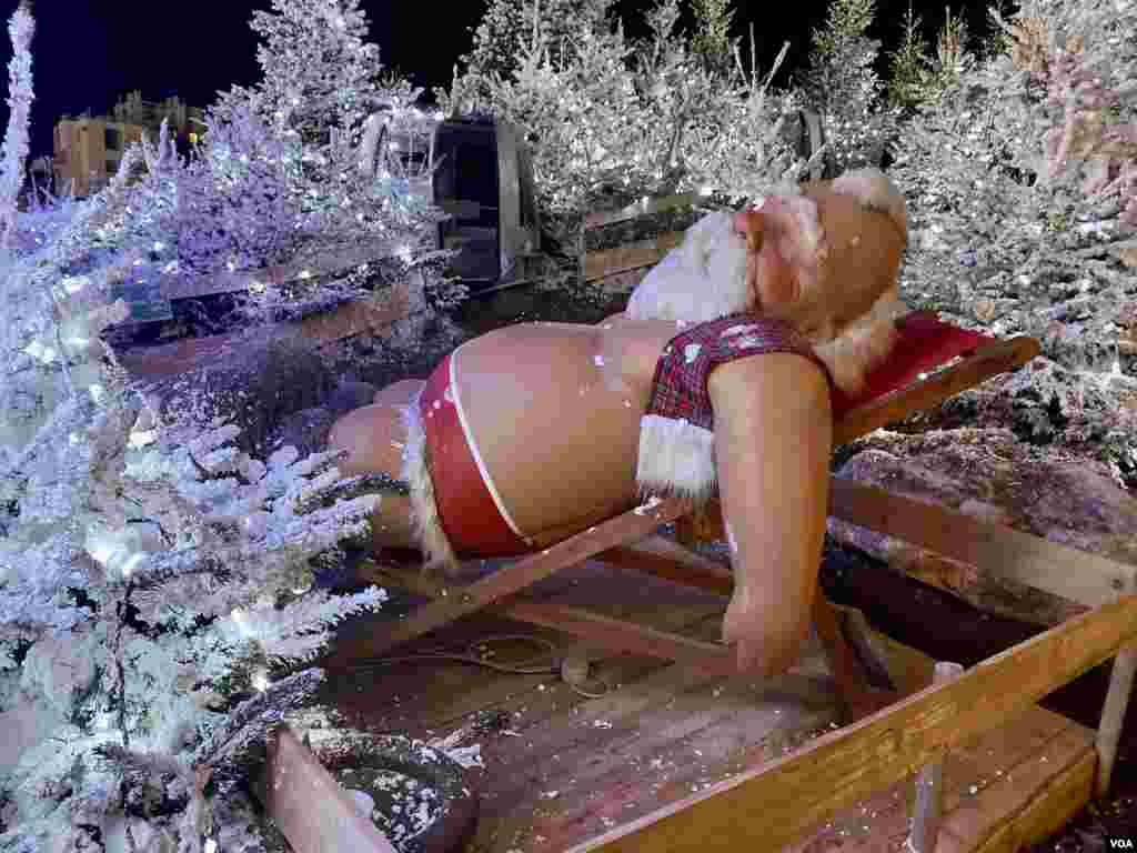 Un acalorado Papá Noel descansa entre abetos nevados en Le Barcarès, Francia.