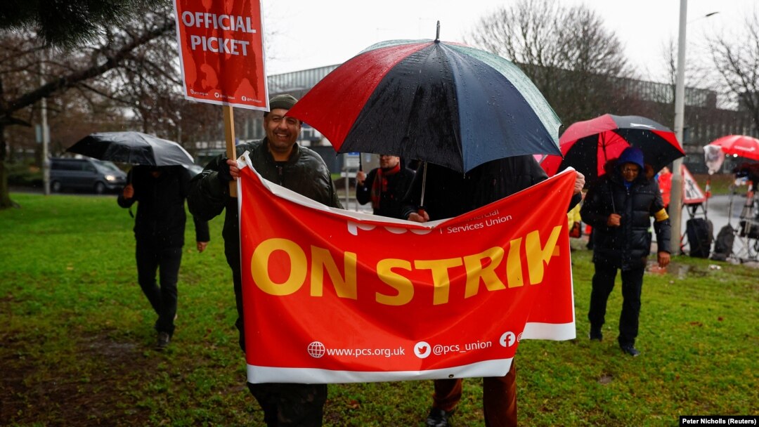 Anggota Serikat Layanan Publik dan Komersial (PCS) memegang spanduk, saat mereka ikut dalam aksi pemogokan pasukan perbatasan di dekat Bandara Heathrow, di London, Inggris, 23 Desember 2022. (Foto: REUTERS/Peter Nicholls)