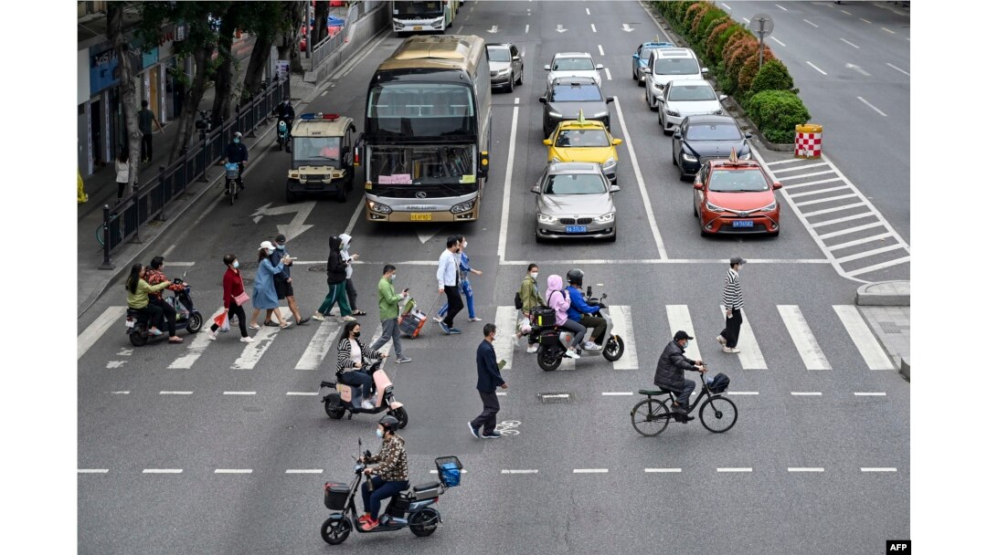 Orang-orang berjalan di seberang jalan di distrik Haizhu, kota Guangzhou, provinsi Guangdong selatan China, setelah pelonggaran pembatasan COVID-19 di kota tersebut, 30 November 2022. (Foto oleh CNS / AFP)