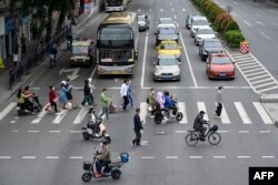 Orang-orang berjalan di seberang jalan di distrik Haizhu, kota Guangzhou, provinsi Guangdong selatan China, setelah pelonggaran pembatasan COVID-19 di kota tersebut, 30 November 2022. (Foto oleh CNS / AFP)