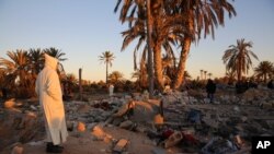 FILE - In this Feb. 19, 2016 photo, people gather after U.S. airstrikes on a house and training camp belonging to the Islamic State group, west of Sabratha, Libya. 