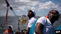 Sibusiso Sizatu (2nd L), skipper of the ArchAngel yacht, checks the rigging while sailing with his crew offshore Cape Town on Nov. 13, 2022. 