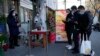 Residents show their health code before they enter a market with some shops re-opening for business as restrictions are eased in Beijing, Dec. 3, 2022. 