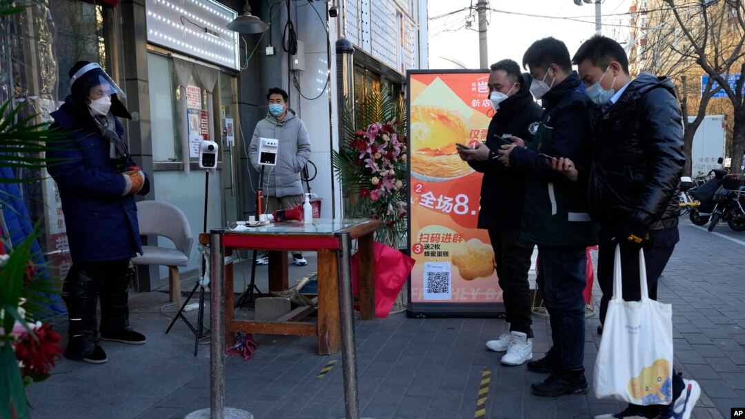 Residents show their health code before they enter a market with some shops re-opening for business as restrictions are eased in Beijing, Dec. 3, 2022. 