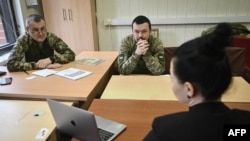Ukrainian servicemen Ihor Soldatenko, left, and Yuriy Kalmutskiy attend an English lesson with teacher Olena Chekryzhova at a military facility in Kyiv, Dec. 21, 2022.