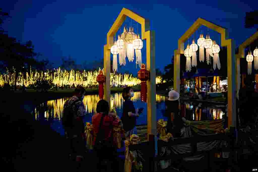People cross a bridge illuminated with lanterns in Suan Luang Rama IX park in Bangkok, Thailand.