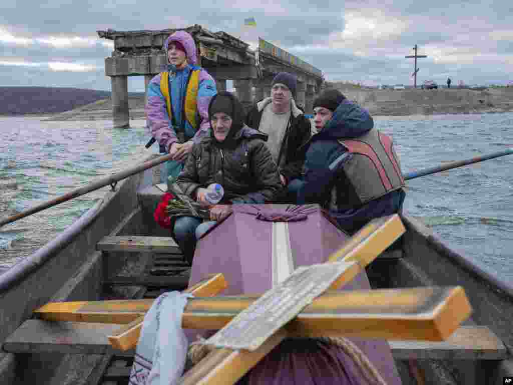 A woman transports the coffin containing her dead son, a soldier who was killed in fighting with Russians, in a boat near Staryi-Saltiv, Kharkiv region, Ukraine, Jan. 4, 2023.