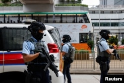 FILE - Armed police stand guard as they escort a prison van that is believed to carry media mogul Jimmy Lai, founder of Apple Daily, to the High Court in Hong Kong, China, Dec. 1, 2022.