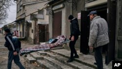 Civiles ucranianos cargan el cuerpo de un hombre de 20 años que murió en un bombardeo ruso en Jersón, Ucrania, el 5 de enero de 2023.