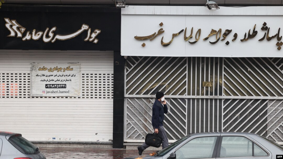 Seorang pria berjalan melewati toko-toko yang tutup di sepanjang jalan Satarkhan di ibu kota Iran, Teheran, 5 Desember 2022. (ATTA KENARE / AFP)