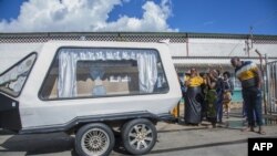Relatives look at a hearse carrying the remains of Zambian student Lemekhani Nyireda at the Kenneth Kaunda International Airport in Lusaka on December 11, 2022