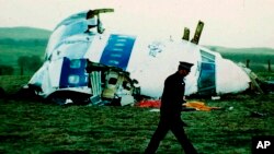 Foto Achiv: Yon polisye mache bo kote avyon Pan Am vol 103 ki tonbe sou vil Lockerbie, peyi Ekos, 21 Desanm 1988. 