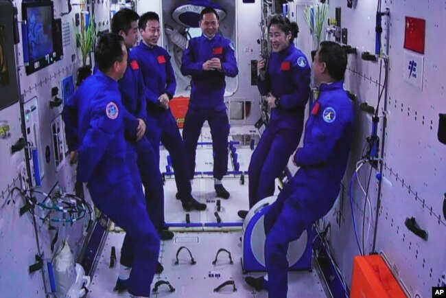 In this photo released by Xinhua News Agency, an image captured off a screen at the Jiuquan Satellite Launch Center in northwest China shows the Shenzhou-15 and Shenzhou-14 crew chatting after a historic gathering in space, Nov. 30, 2022.