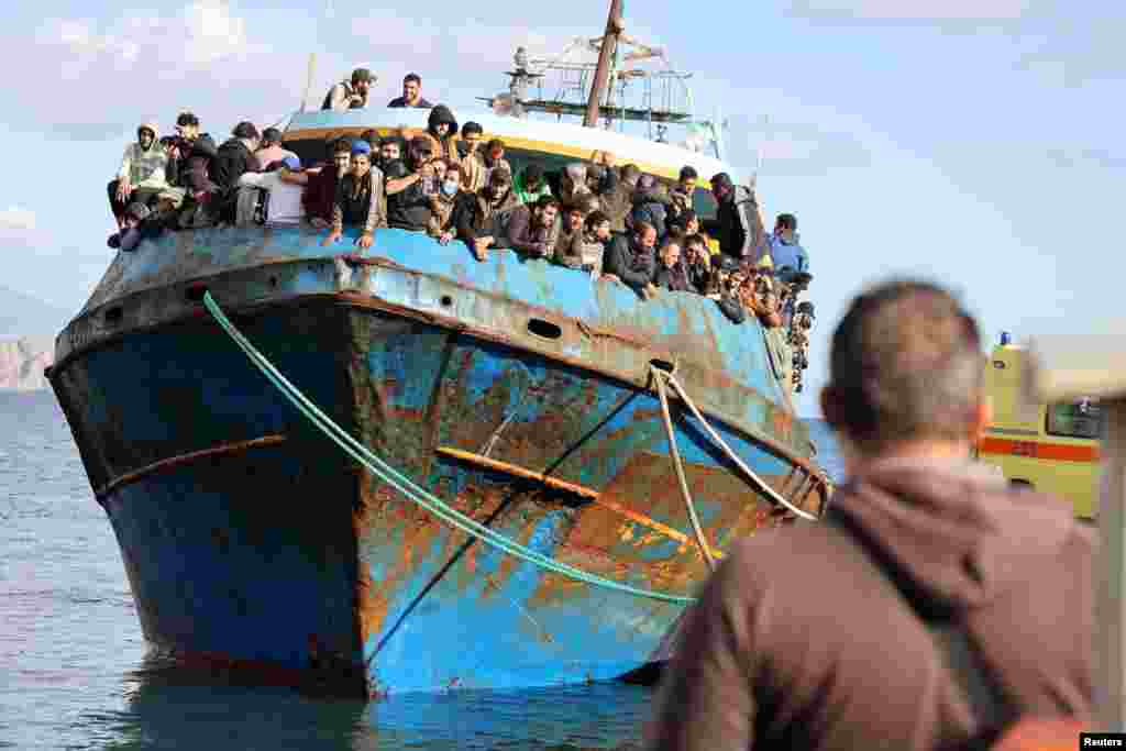 Migrants stand onboard a fishing boat at the port of Paleochora, following a rescue operation off the island of Crete, Greece, November 22, 2022.