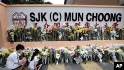 Students place flowers at the entrance of the SJK (C) Mun Choong school in Kuala Lumpur, Malaysia, Sunday, Dec. 18, 2022. Seven female teachers from the school were on an unofficial camping trip at an organic farm that was hit by a landslide, Friday, Dec. 16, 2022.