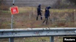 Expertos ucranianos buscan artefactos explosivos sin detonar y minas terrestres junto a la carretera principal a Jersón, Ucrania, el 16 de noviembre de 2022.