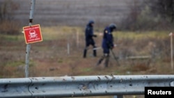 Ukrainian mine experts scan for unexploded ordnance and landmines by the main road to Kherson, Ukraine, Nov. 16, 2022.