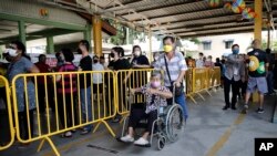 A Malaysian voter on wheel chair arrives to cast her ballot for the general elections at a polling station in Kuala Lumpur, Malaysia, Nov. 19, 2022. 