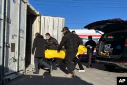 北京一家火葬场的工作人员正在将一具尸体放入冷藏储存装置内。（2022年12月17日）