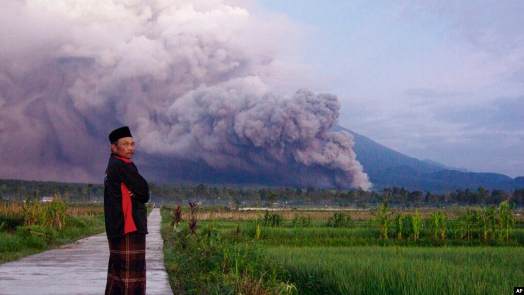 A man looks on as Mount Semeru releases volcanic materials during an eruption Dec. 4, 2022 in Lumajang, Indonesia.