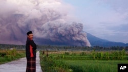 A man looks on as Mount Semeru releases volcanic materials during an eruption Dec. 4, 2022 in Lumajang, Indonesia.