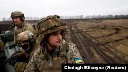 Ukrainian soldiers sit atop cannon on the front line in Ukraine.