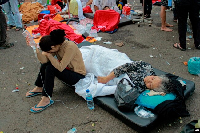 Earthquake survivors are treated outside of a hospital in Cianjur, West Java, Indonesia, Monday, Nov. 21, 2022. (AP Photo/Kholid)