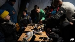 FILE - People charge their phones at a heating tent, a “Point of Invincibility,” a government-built help station that serves food, drinks and warmth in Kherson, Ukraine, Dec. 3, 2022.