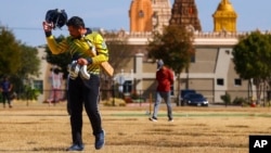Pavan Kumar Machiraju walks off the field after batting during a cricket match between the Dallas Cricket Connections and the Kingswood Cricket Club, as the Karya Siddhi Hanuman Temple is seen in the background, in Frisco, Texas, Oct. 22, 2022. (AP Photo/Andy Jacobsohn)