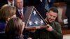 El presidente de Ucrania, Volodymyr Zelenskyy, sostiene una bandera estadounidense regalada por la entonces líder de la Cámara de Representantes de EEUU, Nancy Pelosi, junto a la vicepresidenta Kamala Harris, en el Capitolio, Washington, el 21 de diciembre de 2023.