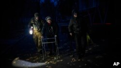 27일 우크라이나 남부 도시 헤르손에서 군인이 대피하는 주민을 돕고 있다.